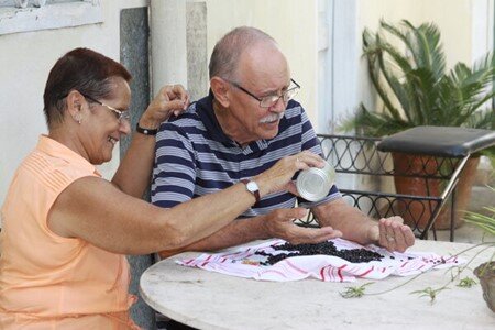 An elderly Cuban couple sits at a table with black beans