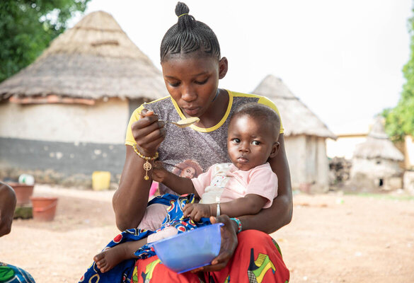 Guinea. A woman beneficiary receiving nutrition assistance through the RESIGUI project in Frenkamaya eating cooked super cereal