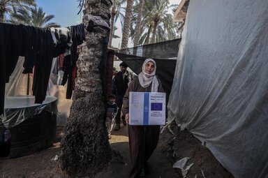 Nadia, a mother, carrying WFP food box